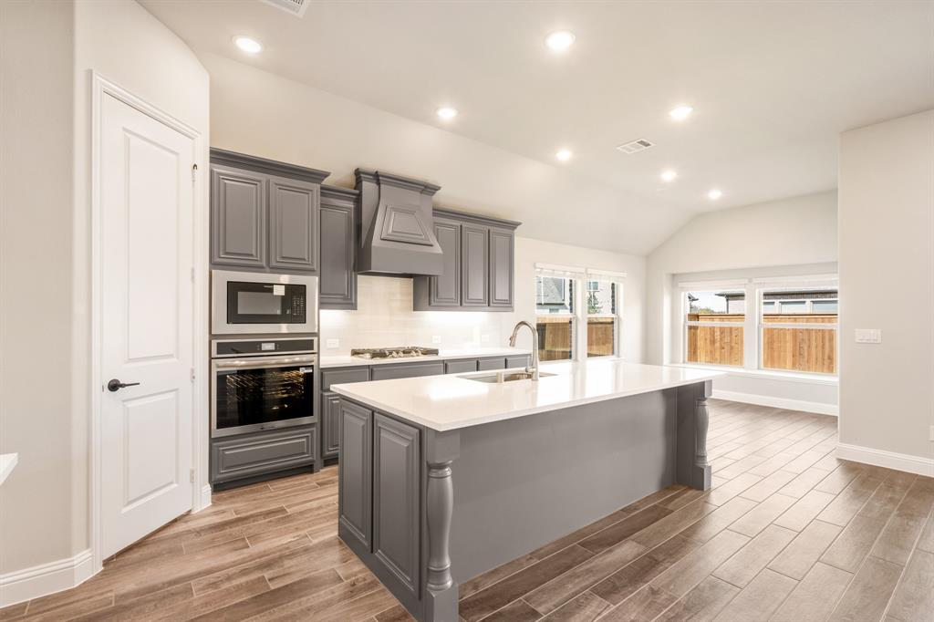 14426 McClint Street Pilot Point, TX 76258 - Photo 10 of 34 a large kitchen with stainless steel appliances granite countertop a stove top oven a refrigerator a sink and dishwasher with wooden floor