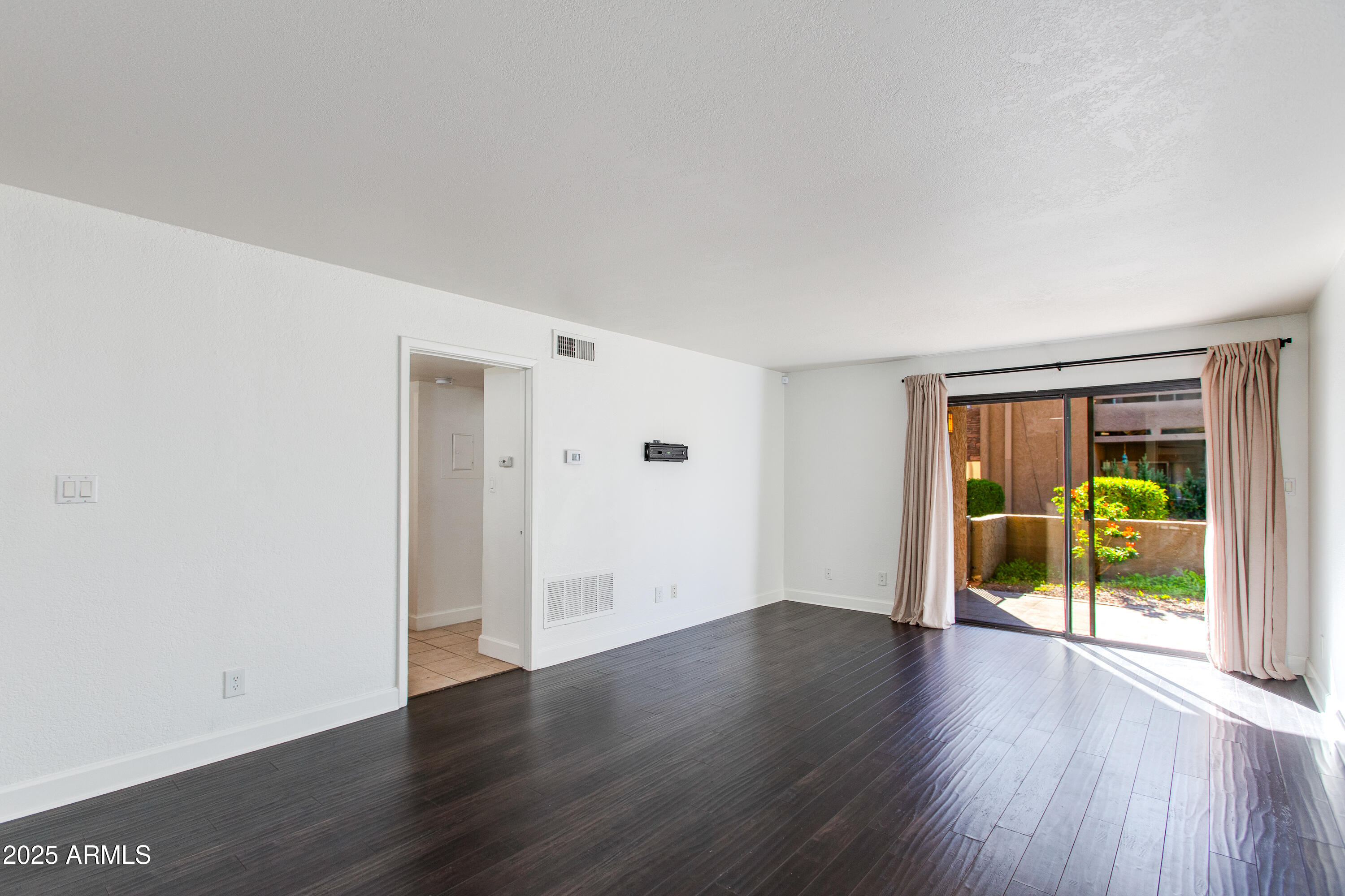 3825 East Camelback Road, Unit 105 Phoenix, AZ 85018 - Photo 2 of 14 an empty room with wooden floor and sliding door
