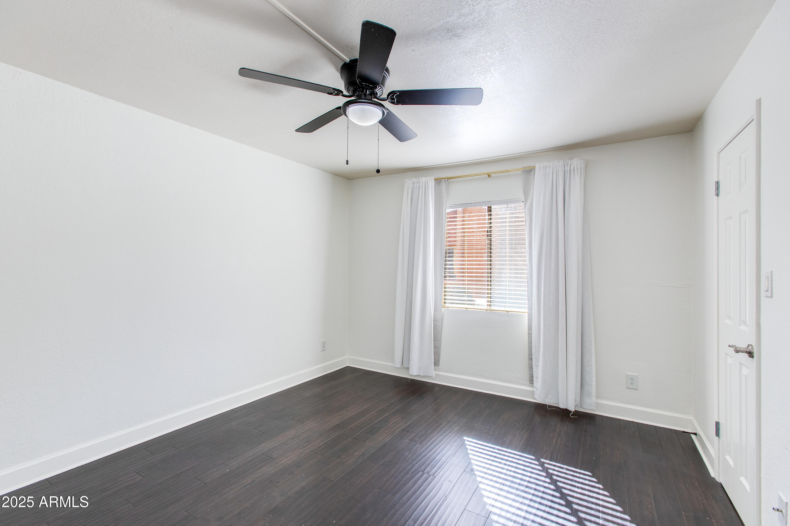 3825 East Camelback Road, Unit 105 Phoenix, AZ 85018 - Photo 6 of 14 a view of empty room with wooden floor and fan