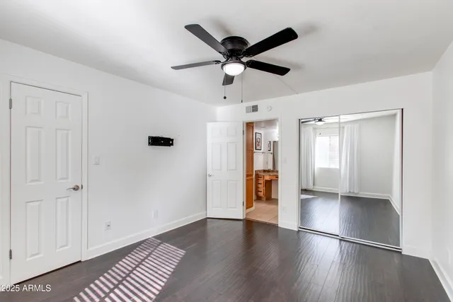 a view of empty room with wooden floor and ceiling fan