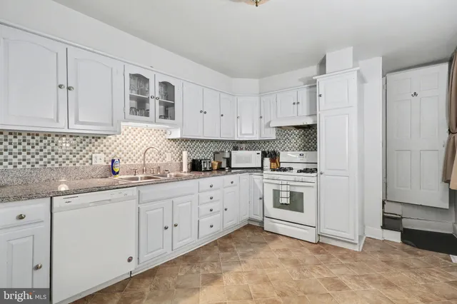 a kitchen with granite countertop white cabinets and white appliances