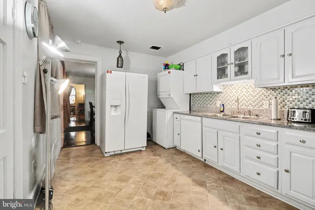 a kitchen with white cabinets and refrigerator