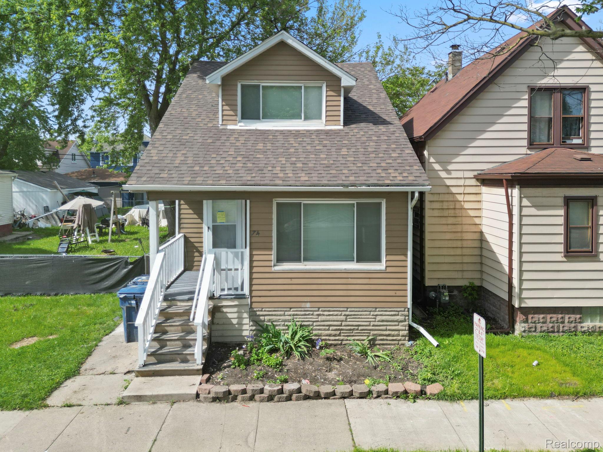 74 Pine Street River Rouge, MI 48218 - Photo 1 of 28 View of front of house featuring a front yard, roof with shingles, and covered porch