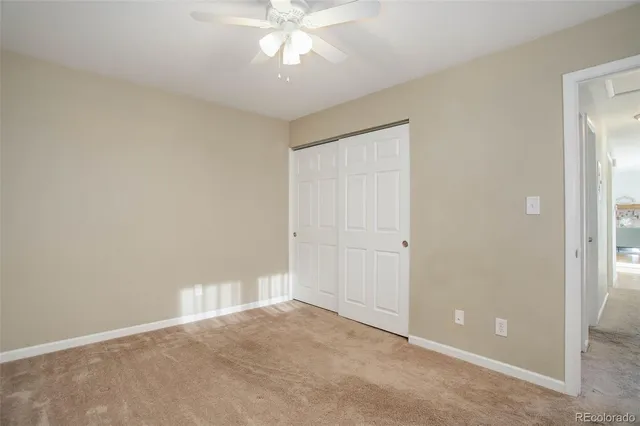an empty room with a ceiling fan and a window