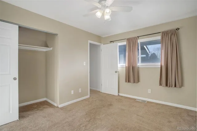 a view of an empty room with window and closet area