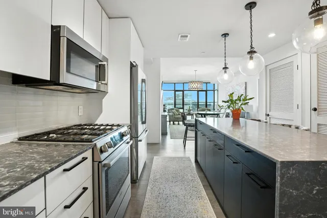 a kitchen with stainless steel appliances granite countertop a sink a stove and a wooden floors