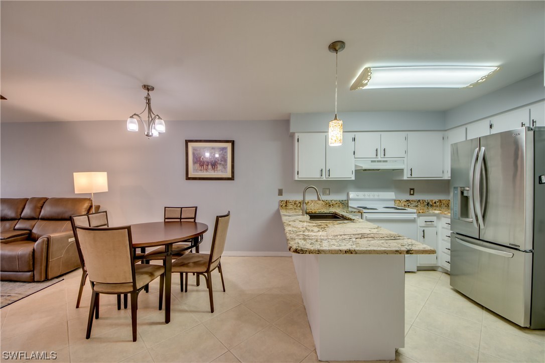 1100 Pondella Road, Unit 814 Cape Coral, FL 33909 - Photo 7 of 36 a kitchen with stainless steel appliances granite countertop a table chairs and a refrigerator