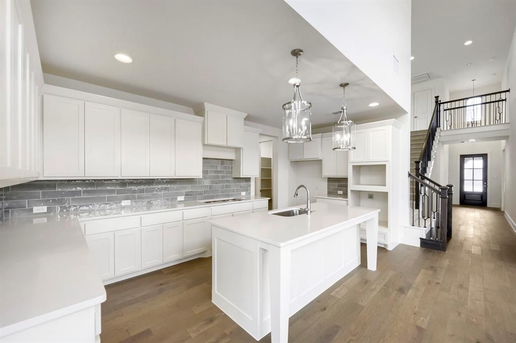 11548 Wulstone Road Haslet, TX 76052 - Photo 8 of 26 Contemporary kitchen featuring white cabinetry, light-toned countertops, a full-height gray tile backsplash, and wood-finish flooring