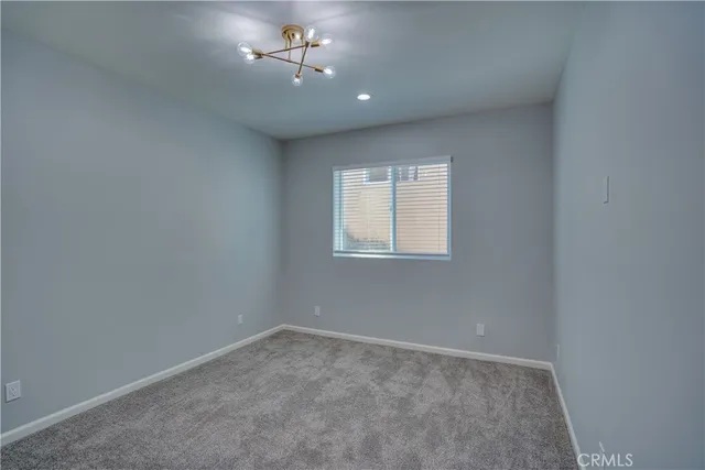 an empty room with a chandelier fan and windows
