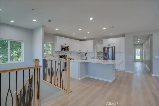 a open kitchen with white cabinets wooden floor and stainless steel appliances