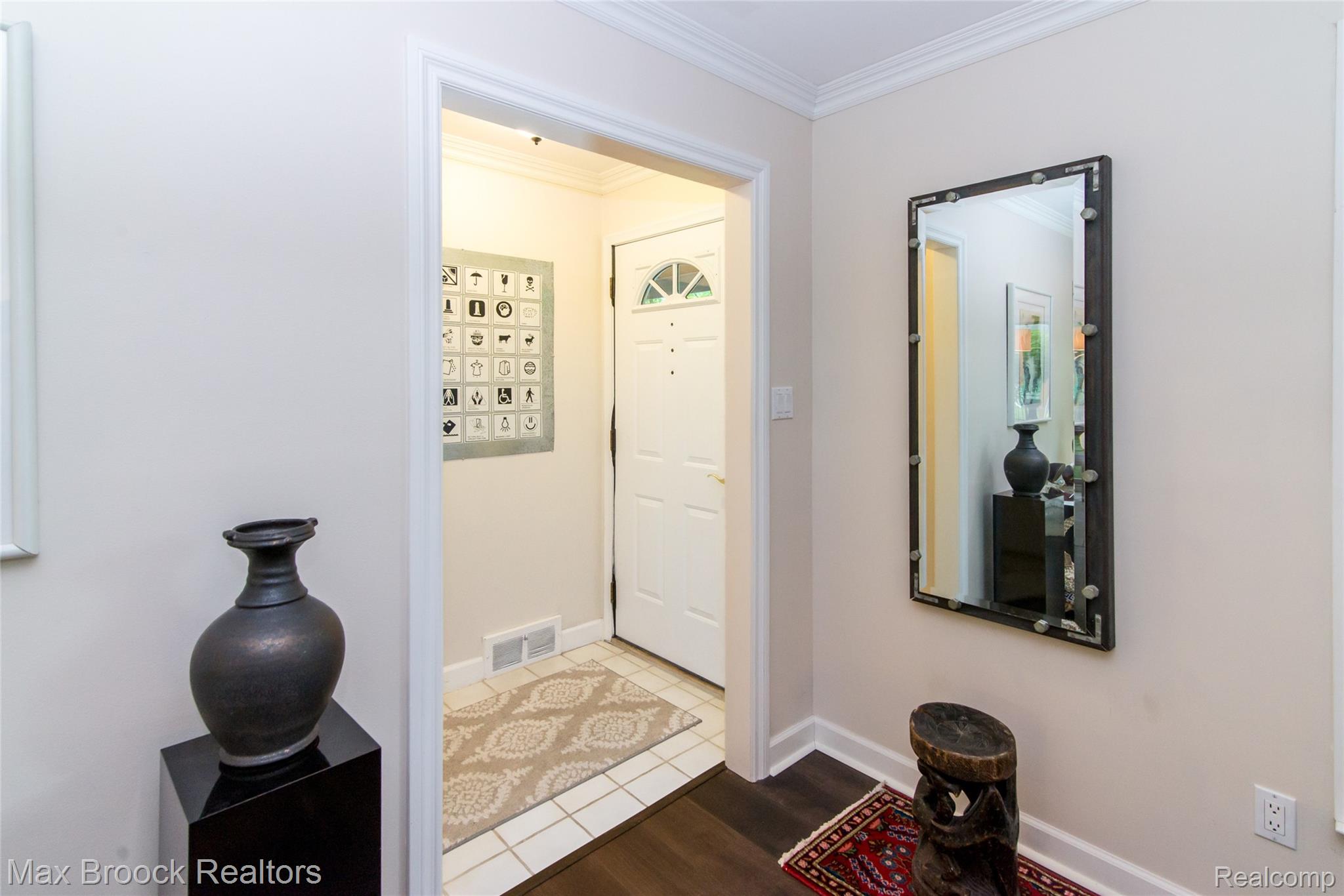 6799 East Dartmoor Road West Bloomfield, MI 48322 - Photo 2 of 36 Entryway featuring a white paneled door with a decorative transom window, crown molding, and contrasting wood-finish flooring