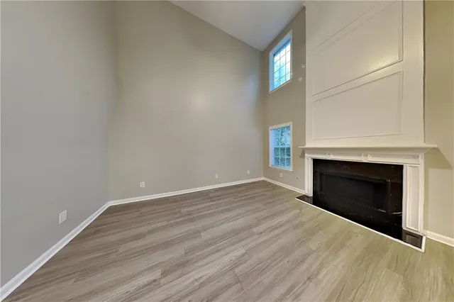 a view of an empty room with wooden floor fireplace and a window