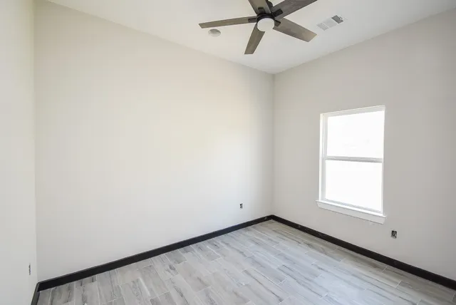 a view of an empty room with a window and a ceiling fan