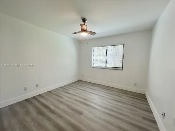 an empty room with wooden floor chandelier fan and windows