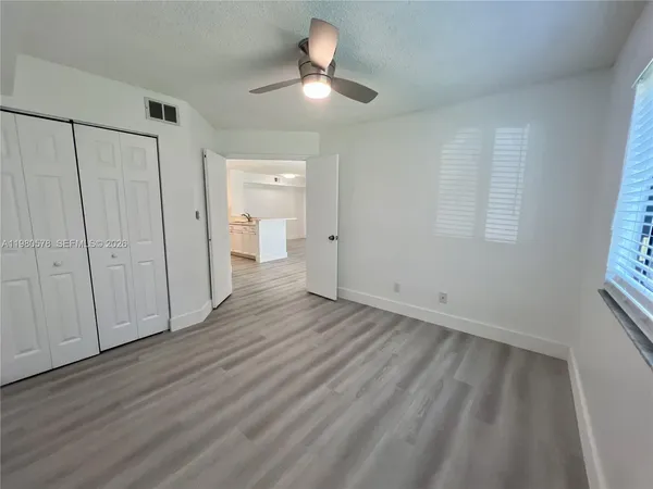 a view of empty room with wooden floor and fan