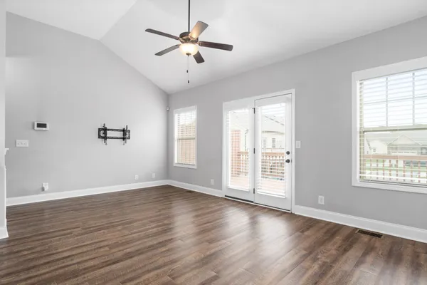 an empty room with wooden floor and windows