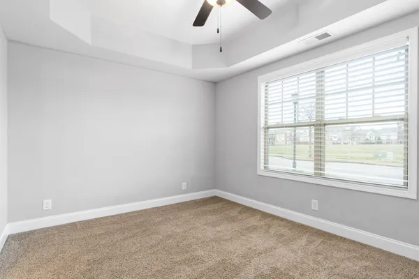 an empty room with a window and ceiling fan