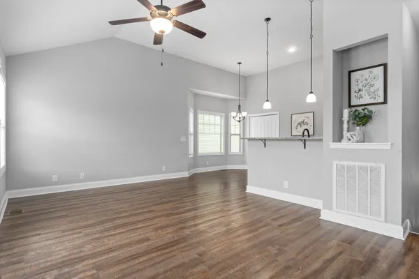 a view of an empty room with window and wooden floor
