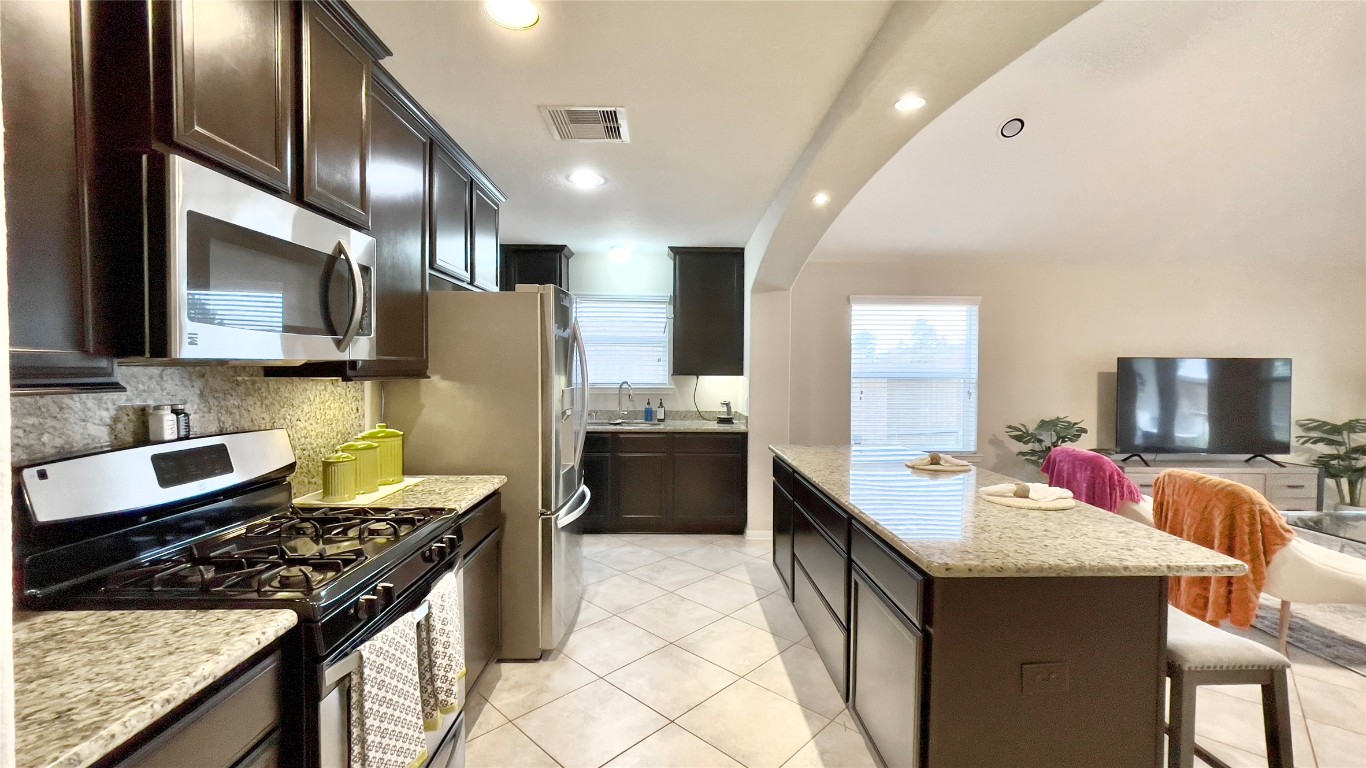 21618 Ivory Gate Lane Katy, TX 77449 - Photo 7 of 32 a large kitchen with stainless steel appliances granite countertop a sink stove and refrigerator
