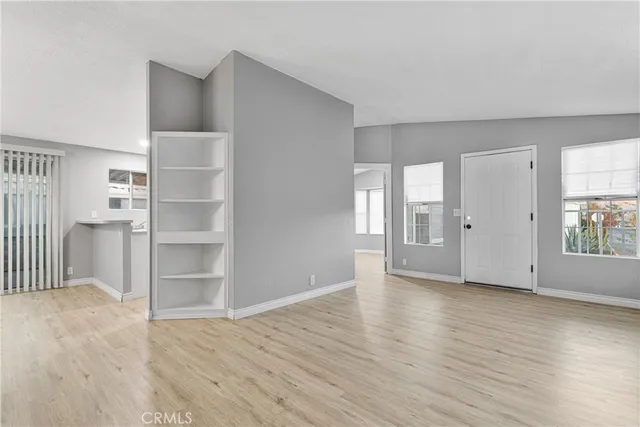 a view of an empty room with window and wooden floor