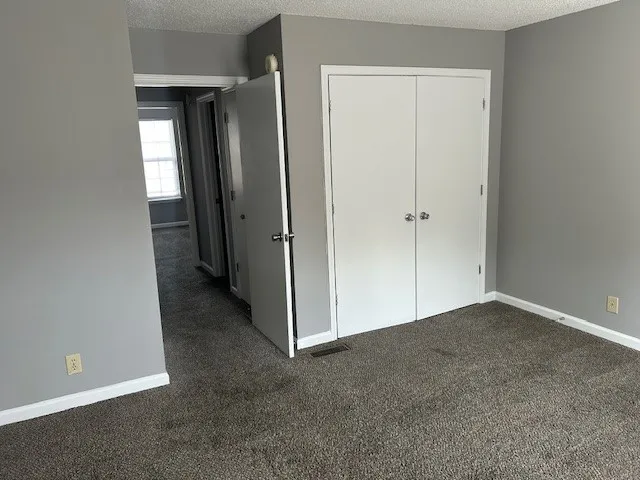 a view of an empty room with closet and a bathroom