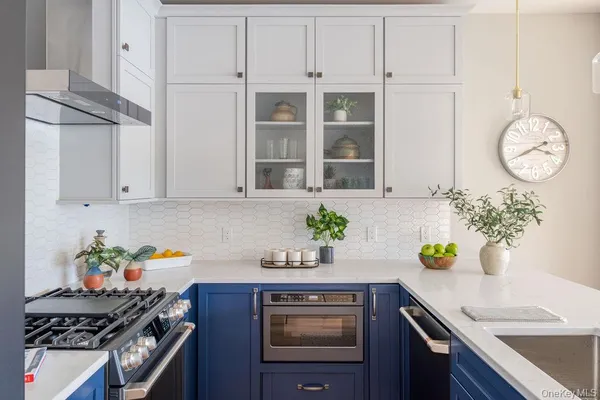 a kitchen with stainless steel appliances granite countertop a sink a stove and a white cabinets