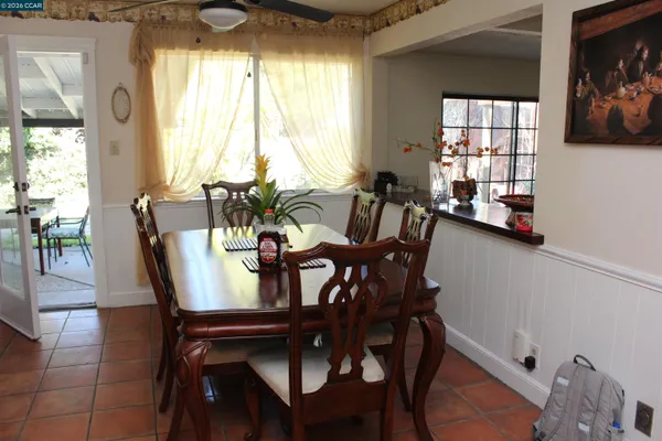 a kitchen with stainless steel appliances granite countertop a dining table chairs and a refrigerator