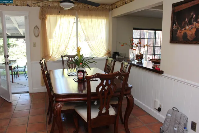 a kitchen with stainless steel appliances granite countertop a dining table chairs and a refrigerator