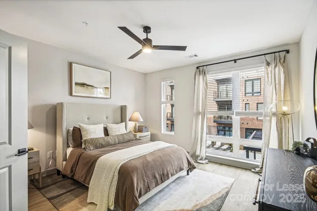 a spacious bedroom with a bed a couch and a large window