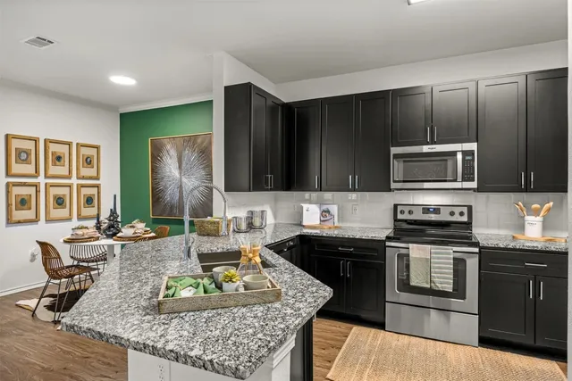 a kitchen with stainless steel appliances granite countertop a sink stove and cabinets