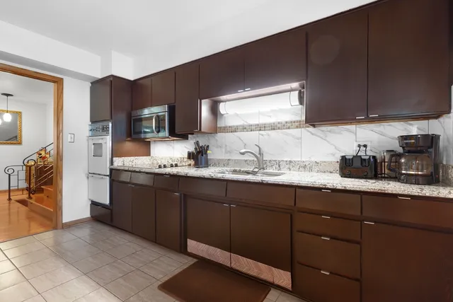 a kitchen with granite countertop a sink cabinets and stainless steel appliances