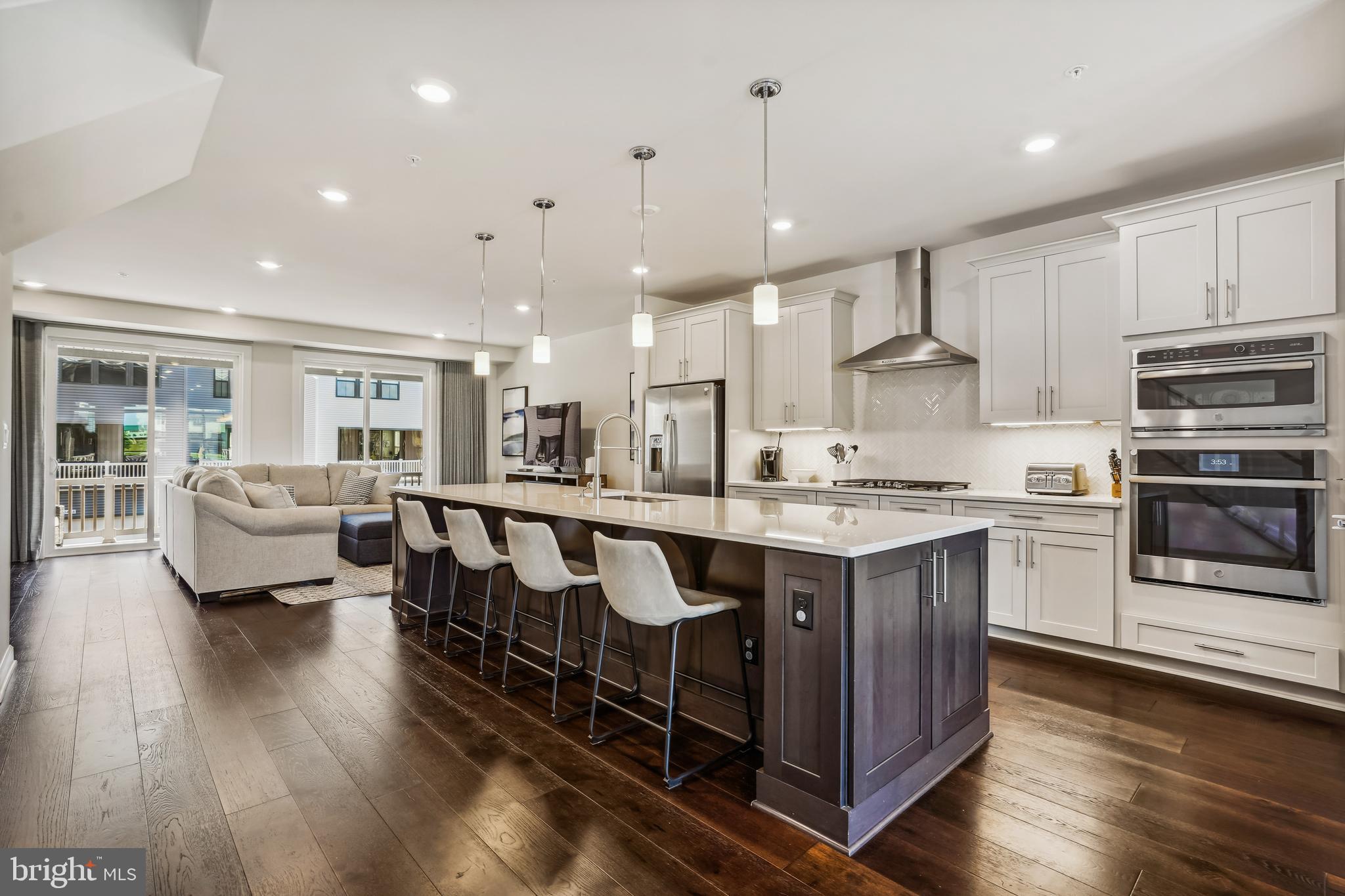 43469 Grandmoore Street Ashburn, VA 20148 - Photo 14 of 62 a large kitchen with stainless steel appliances kitchen island granite countertop a stove a sink and a living room with wooden floor
