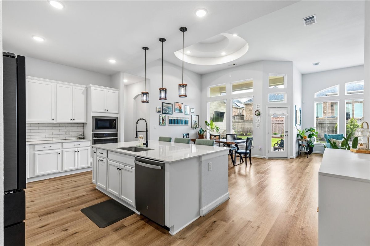 1029 Wild Pecan Loop Buda, TX 78610 - Photo 6 of 37 a kitchen with stainless steel appliances kitchen island granite countertop a stove a sink a refrigerator and white cabinets with wooden floor