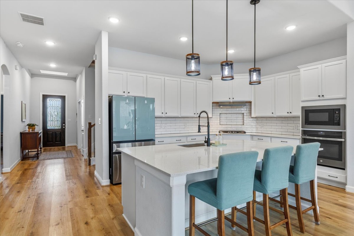 1029 Wild Pecan Loop Buda, TX 78610 - Photo 8 of 37 a kitchen with stainless steel appliances kitchen island granite countertop a table chairs refrigerator and microwave