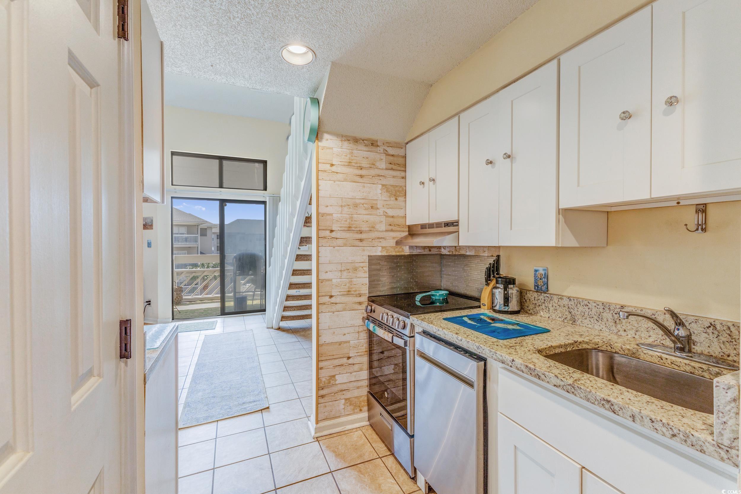 1100 Possum Trot Road, Unit G326 North Myrtle Beach, SC 29582 - Photo 3 of 21 Kitchen featuring a textured ceiling, white cabinetry, light tile patterned flooring, appliances with stainless steel finishes, and light stone counters
