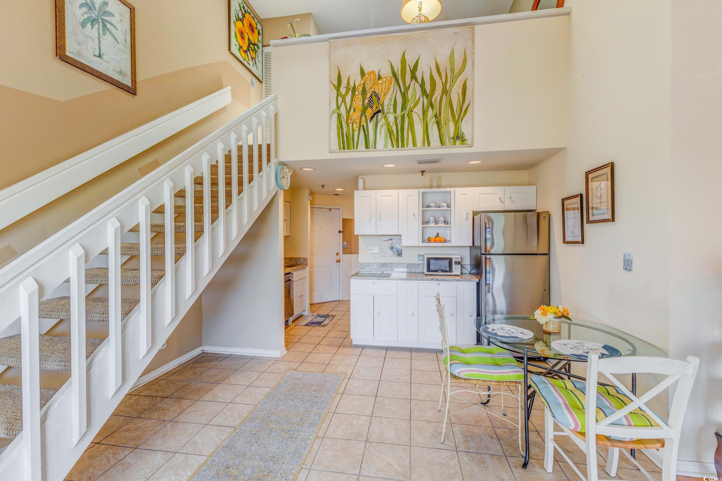 1100 Possum Trot Road, Unit G326 North Myrtle Beach, SC 29582 - Photo 8 of 21 Kitchen featuring stainless steel appliances, a high ceiling, open shelves, white cabinets, and light tile patterned flooring