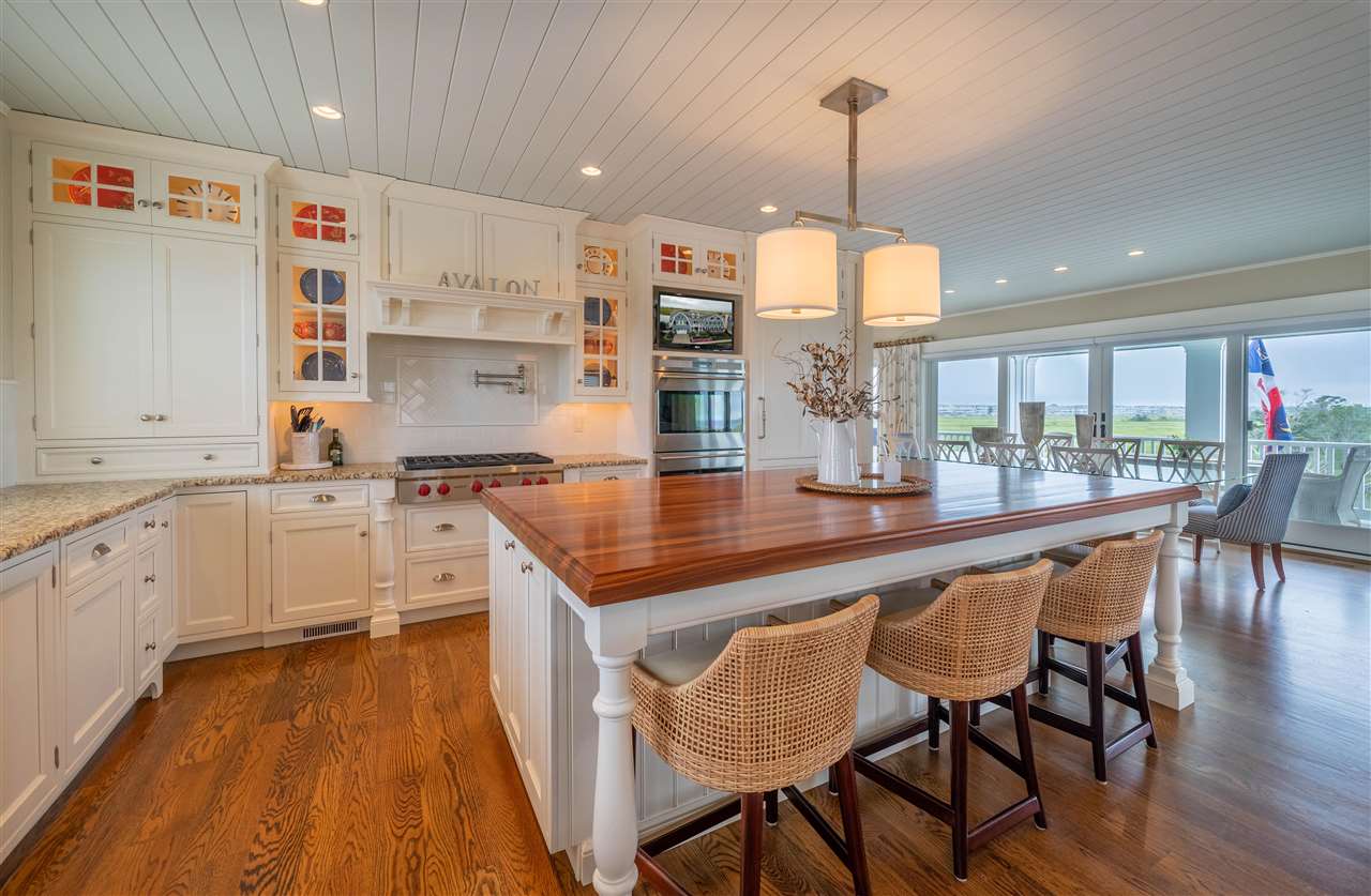 498 7th Street Avalon, NJ 08202 - Photo 16 of 36 a kitchen with stainless steel appliances granite countertop a stove top oven a sink dishwasher and white cabinets with wooden floor