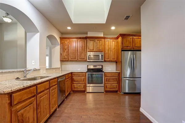 a large kitchen with stainless steel appliances granite countertop a refrigerator and a stove top oven