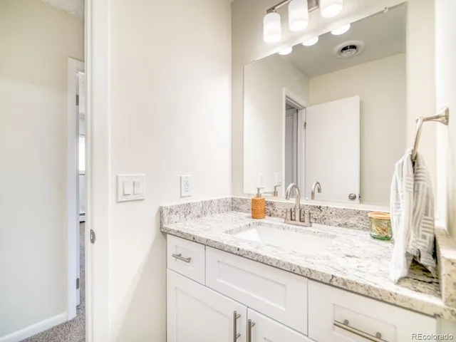 a bathroom with a granite countertop sink and a mirror