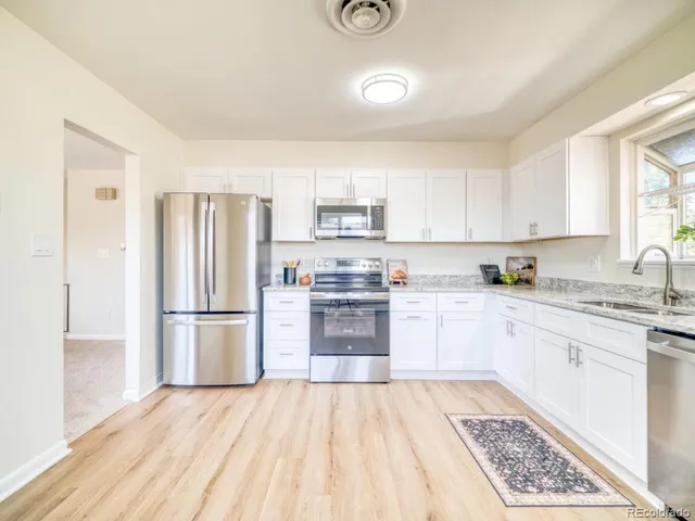 a kitchen with granite countertop a refrigerator stove and sink