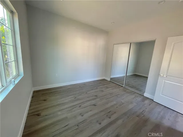 an empty room with wooden floor and window