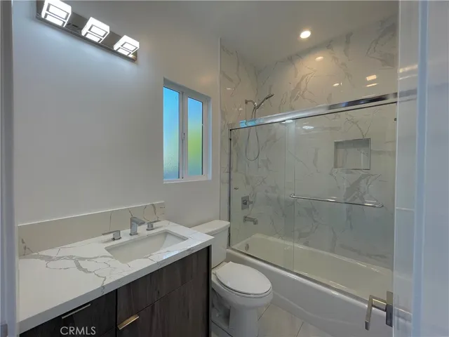 a bathroom with a bathtub shower sink vanity and toilet