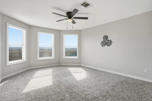 an empty room with windows and fan