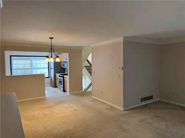 an empty room with chandelier fan and windows