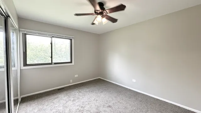 an empty room with a window and a fan