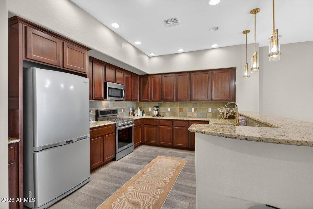 4777 South Fulton Ranch Boulevard, Unit 2035 Chandler, AZ 85248 - Photo 18 of 51 a kitchen with stainless steel appliances granite countertop a refrigerator a sink dishwasher a oven with wooden cabinets and a granite counter tops