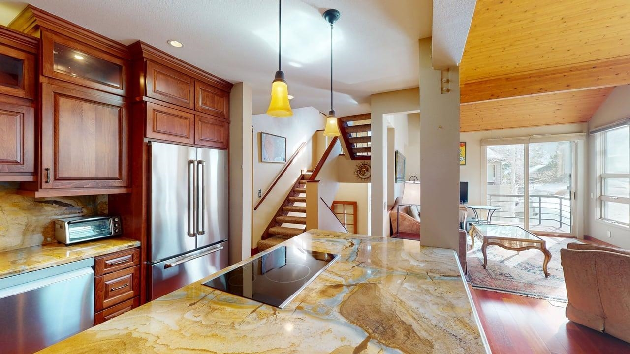 3600 Chateau Road, Unit 2 Mammoth Lakes, CA 93546 - Photo 27 of 27 Kitchen featuring light stone counters, stainless steel appliances, hanging light fixtures, open floor plan, and hardwood / wood-style floors