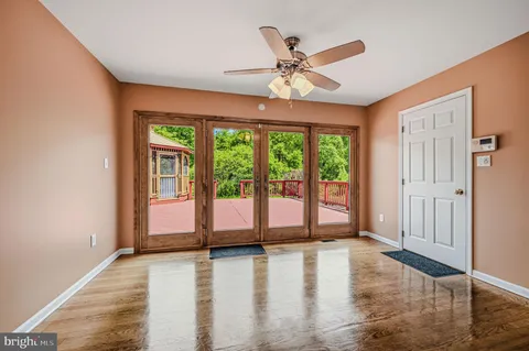 a view of a livingroom with wooden floor a ceiling fan and window