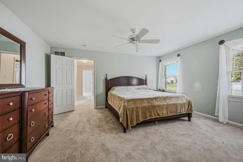 a spacious bedroom with a bed a dresser and a window