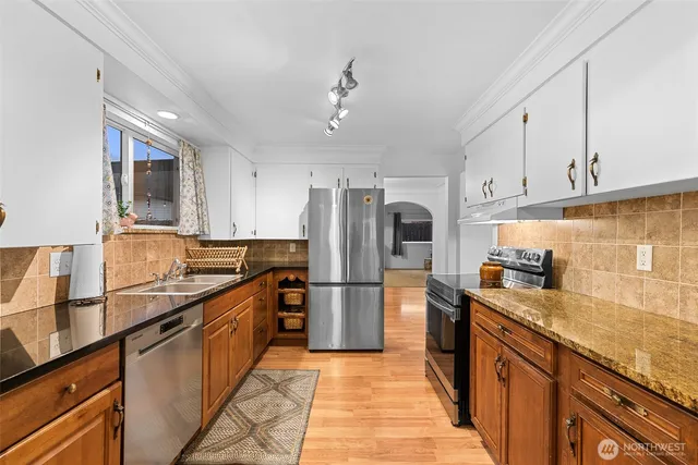 a kitchen with stainless steel appliances granite countertop a sink a stove and a refrigerator